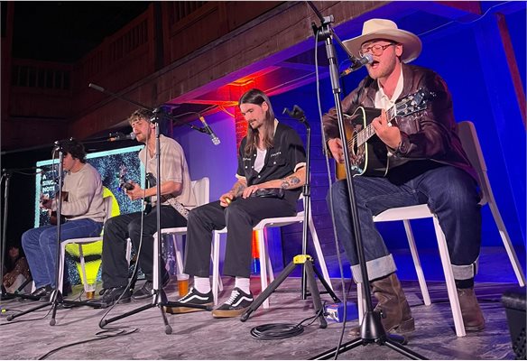 Four band members sat on chairs playing instruments