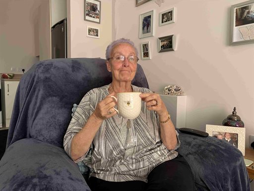 A woman holding a cup of team in a chair in a living room