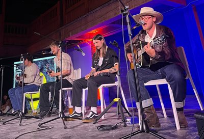 Four band members sat on chairs playing instruments