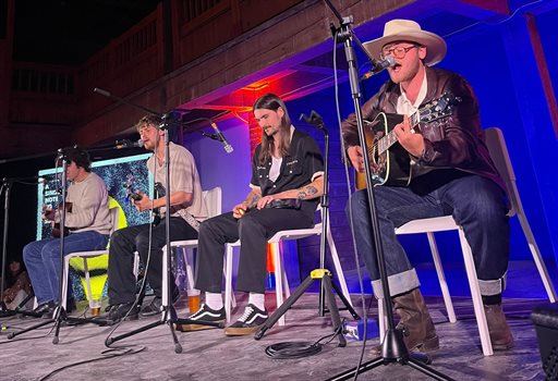 Four band members sat on chairs playing instruments