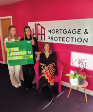 Two girls standing holding a sign saying Future Apprentices for Business grant and a lady say next to a sign sayiing Mortgage and protection
