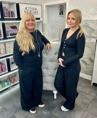 Two ladies stood leaning on a desk in a hairdressers