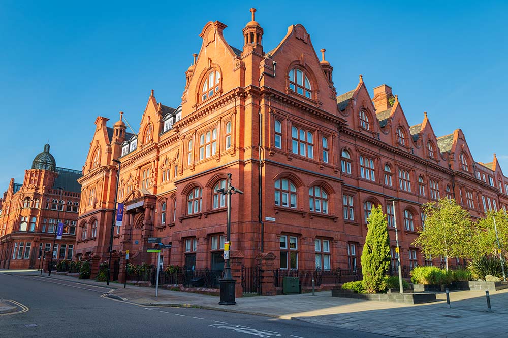 Victorian red-brick civic building with ornate gables and arched windows on a quiet street in daylight.