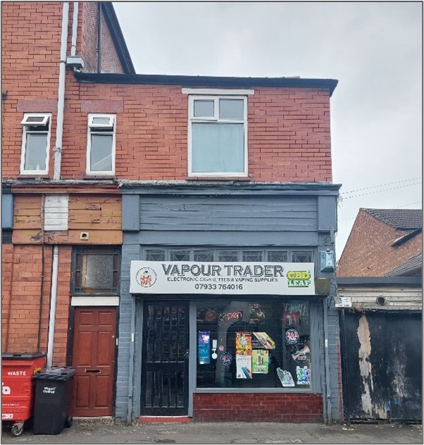 Contemporary photo of the front of Vapour Trader. Two storey building with a sign on the front.