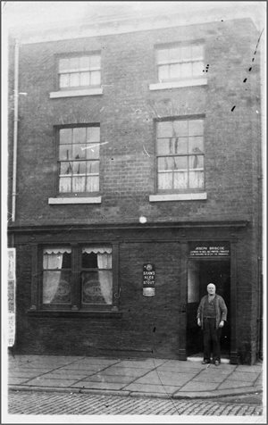 A man stood in the doorway of 101 Bradshawgate, a 3 storey building in a black and white photo