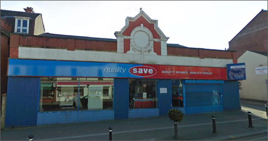 Street view of a Quality Save shop with a blue and red storefront, large display windows, and a decorative gable above the entrance