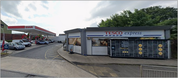 A contemporary photograph of a Tesco Express shop.  Single storey building on the corner of a road.