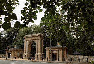 Large stone archway with two lodges either side backing on to woodland