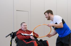 Support worker holding a hoola hoop with a person with a disability